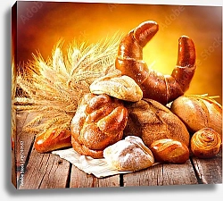 Постер Выпечка и пучок пшеничных колосков на деревянном столе