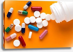 Постер Разноцветные таблетки и капсулы рассыпаны на оранжевом фоне