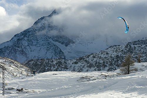 Лыжник практикуется в сноукайтинге на фоне гор