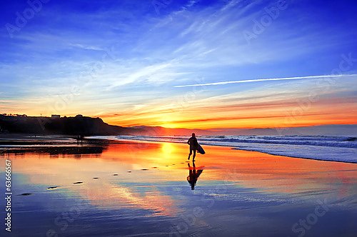 Серфер на пляже перед закатом