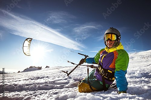 Счастливый сноубордист с кайтом лежит в сугробе