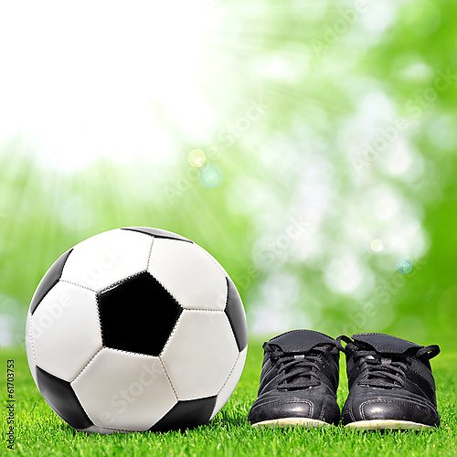 Футбольный мяч и бутсы на зеленой траве