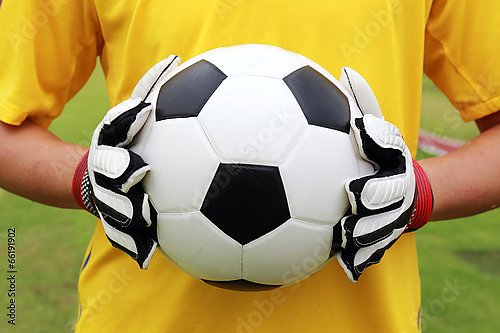 Футболист в желтой футболке с мячом