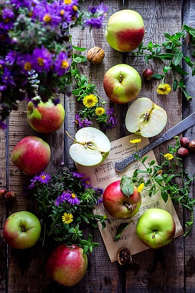 Садовые яблочки, полевые цветы, орехи и ноты на столе