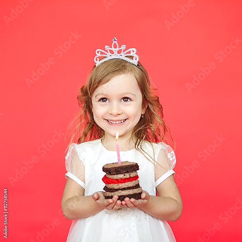 Счастливая девочка держит маленький торт со свечкой