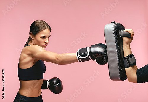 Девушка боксер в перчатках на розовом фоне