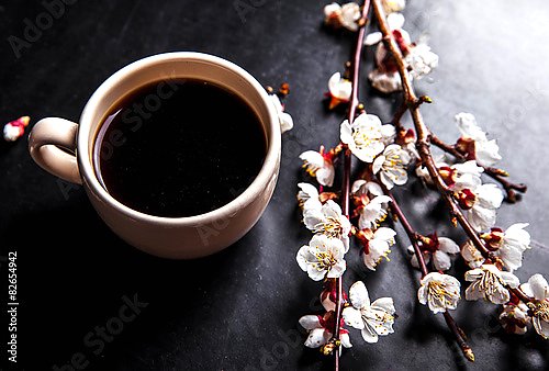 Чашка кофе и ветка цветущей вишни