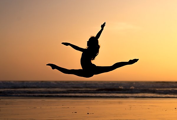 Силуэт гимнастки в прыжке на закате