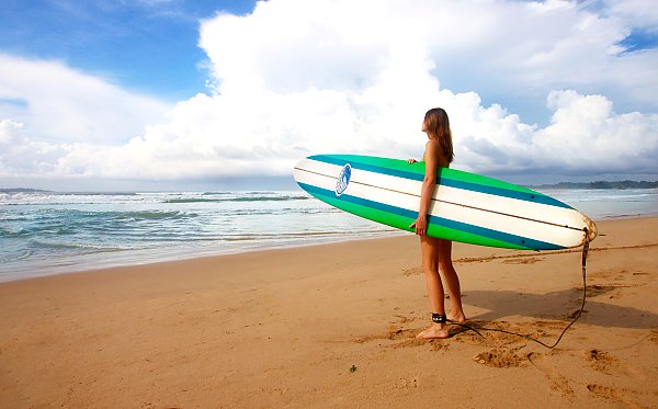 Девушка с доской для серфинга на пляже