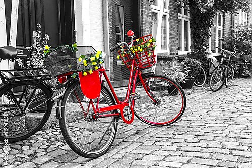 Красный велосипед на чёрно-белой мощеной улице в старом городе