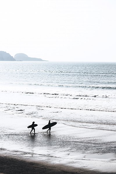 Силуэты двух серферов, идущих к морю