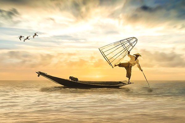 Азиатский рыбак в лодке с сетью