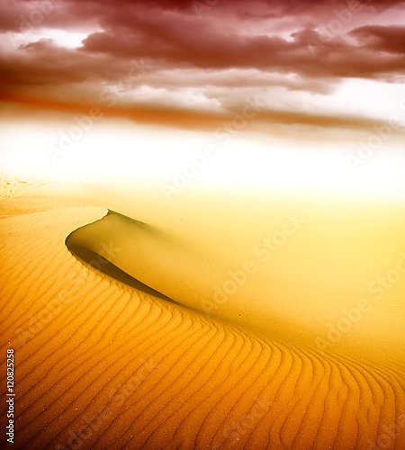 Песчаная дюна под оранжевыми облаками