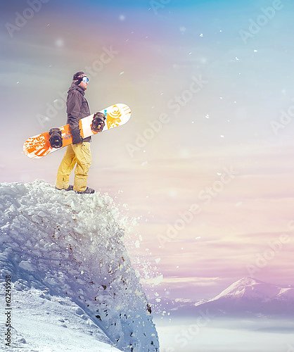 Сноубордист стоящий на вершине скалы