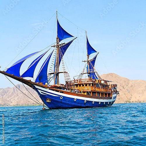 Старинный деревянный корабль с синими парусами