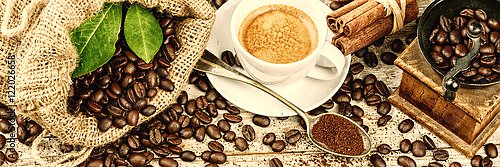 Чашка горячего черного кофе со старой деревянной кофемолкой и рассыпанными зёрнами