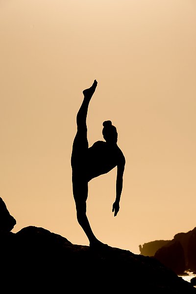 Силуэт гимнастки, стоящей на одной ноге на закате