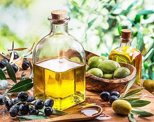 Оливковое масло и ягоды на деревянном столе под оливковым деревом