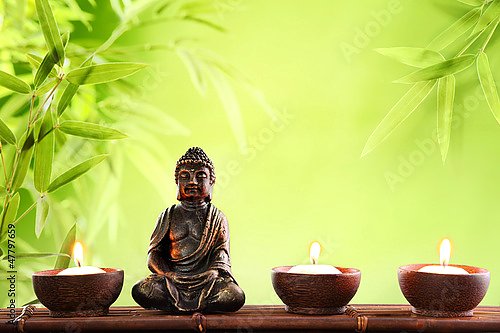 Будда и свечки на фоне бамбуковых листьев