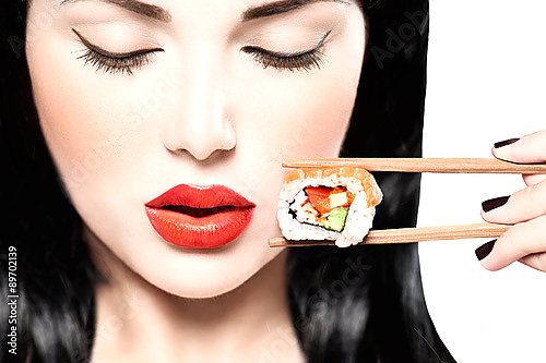 Девушка ест нигири суши палочками для еды