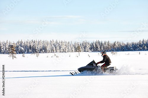 Человек на спортивном снегоходе в финской Лапландии в солнечный день