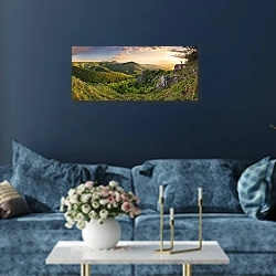 «Человек на фоне заката в горах» в интерьере стильной синей гостиной над диваном