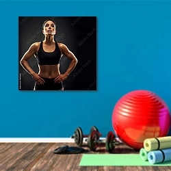 «Спортивная девушка с натренированным телом» в интерьере фитнес-зала с голубой стеной