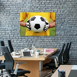 «Футболист в желтой футболке с мячом» в интерьере современного офиса с черной кирпичной стеной
