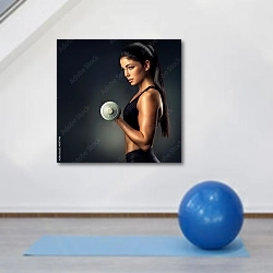 «Спортивная женщина держащая гантель» в интерьере фитнес-зала с голубым инвентарем