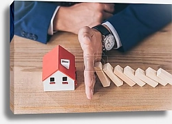 Постер cropped view of risk manager protecting house model from falling wooden blocks with hand