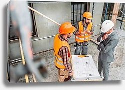 Постер high angle view of confused builders and architect discussing building plan at construction site