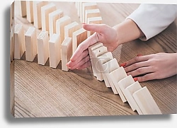 Постер partial view of risk manager blocking domino effect of falling wooden blocks