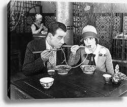Постер Couple sharing a noodle in a restaurant