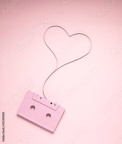 Розовая кассета с лентой в форме сердца на розовом фоне