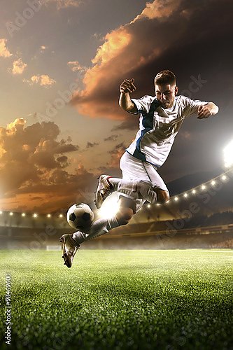 Футболист подбрасывает мяч в прыжке