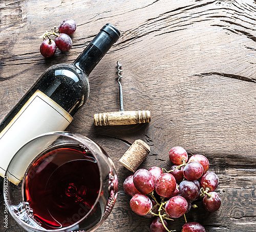 Винный бокал, бутылка вина и виноград на деревянном фоне