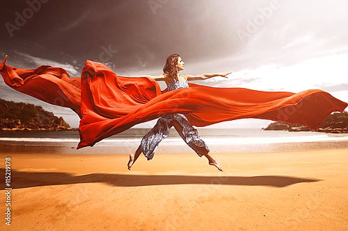 Женщина на пляже в струящейся красной ткани