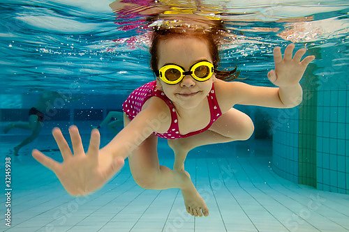 Маленькая девочка под водой в бассейне