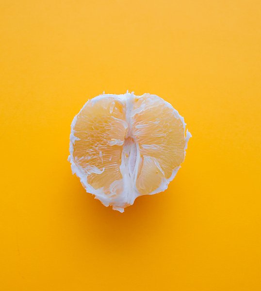 Очищенный апельсин на желтом фоне