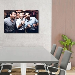 «Three men sing at a karaoke club. Young people have fun in a nightclub. They are very cheerful and they smile.» в интерьере современного офиса над столом для конференций